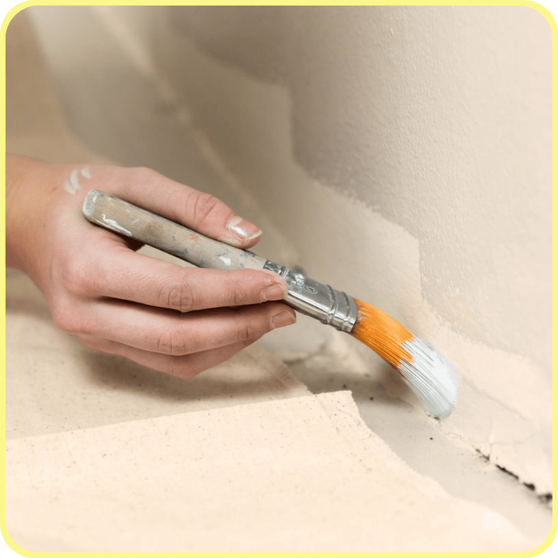 close up of a hand holding a paint brush and cutting the edge of a wall